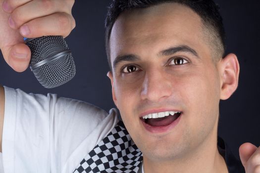 Young black-haired man dressed in black and white performs singing to microphone