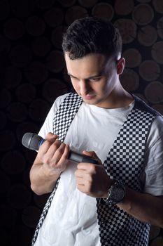 Young black-haired man dressed in black and white performs singing to microphone