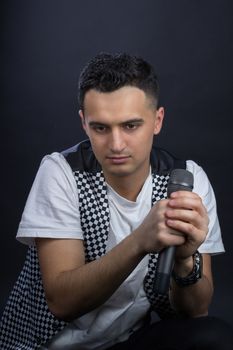 Young black-haired man dressed in black and white poses singing to microphone