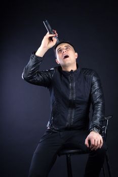 Young black-haired man dressed in black and white poses singing to microphone