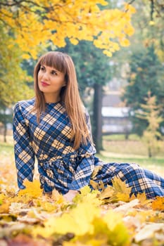 beautiful, dreamy girl with long straight hair in a blue long dress in the park in autumn