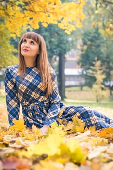 beautiful, dreamy girl with long straight hair in a blue long dress in the park in autumn