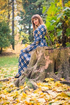 beautiful, dreamy girl with long straight hair in a blue long dress in the park in autumn