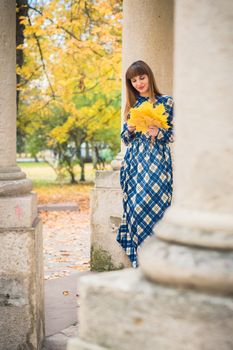 beautiful, dreamy girl with long straight hair in a blue long dress in the park in autumn