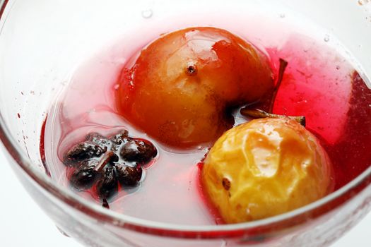 Red apple in rose syrup with anise over isolated white background