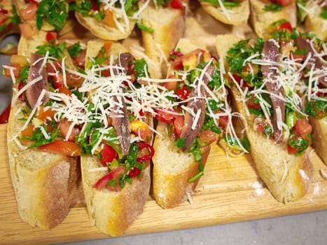 Typical classical Italian Bruschetta with tomatoes, herbs and oil on toasted garlic cheese bread on a wooden tray