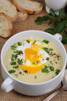 potato cream soup with bacon and poached eggs, herbs, spices