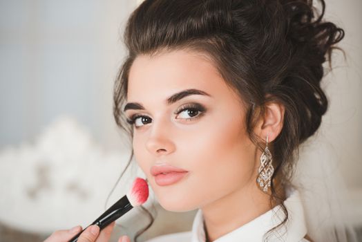 Artist applying blush to wedding make up for bride