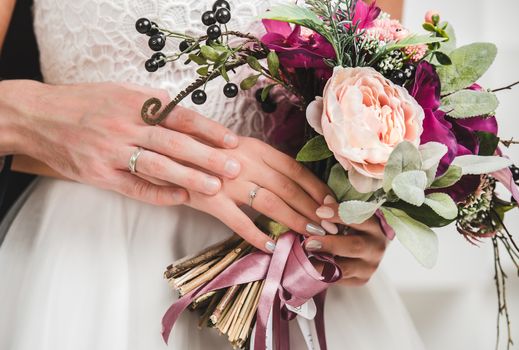 Beautiful wedding bouquet in bride's and groom's hands close up view