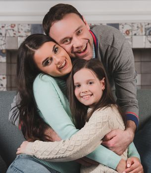 Family portrait of happy parents and their daughter at home