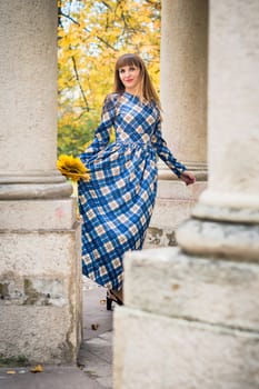 beautiful, dreamy girl with long straight hair in a blue long dress in the park in autumn