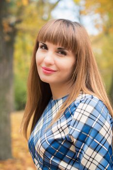 beautiful, dreamy girl with long straight hair in a blue long dress in the park in autumn