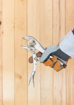 Working hand in glove holding a Adjustable wrench with wall wood background