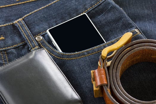 Top view of wallet and leather belt and smartphone on denim jeans pocket