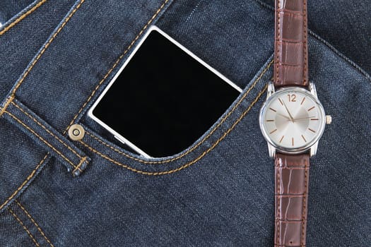 Top view of wrist watch on brown leather strap and smartphone on jeans pocket
