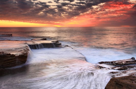 Ocean waves smash onto the rocks and then retreat in a marvelous dispolay or waterfall cascades at Maroubra, near Sydney Australia.