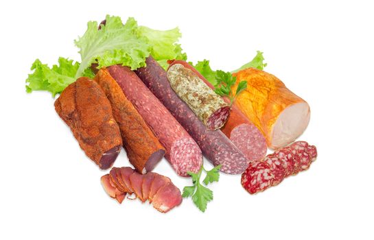 Partly sliced two pieces of the dried pork tenderloin, different varieties of cooked smoked and dry smoked sausages, salami, ham with turkeys, parsley and lettuce on a light background  
