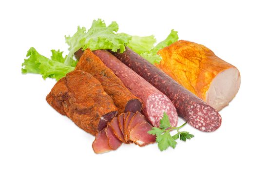 Partly sliced two pieces of the dried pork tenderloin, two varieties of dry smoked sausage and ham with turkeys with parsley twig and lettuce on a light background  
