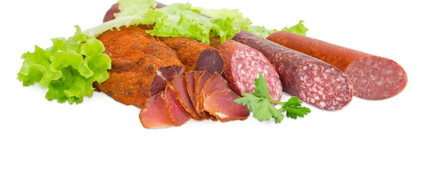 Partly sliced pieces of the dried pork tenderloin and the different cooked smoked and dry smoked sausages with greens closeup on a light background  
