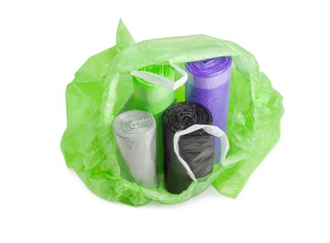 Several plastic disposable garbage bags of different sizes and colors in rolls in an open one of them with handles, made from ribbons which may be tied, on a light background
