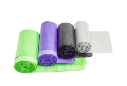 Several rolls of plastic disposable garbage bags of different sizes and colors including biodegradable on a light background
