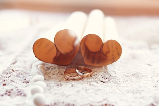 gold wedding rings bride and groom on the background of hearts made of paper