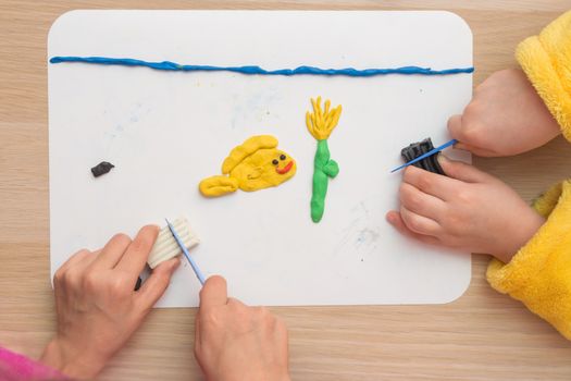 Page Online Two children are molded from clay on board fish and underwater flower in the sea, the top view