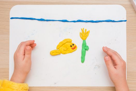 Child blinded pas board for modeling fish and underwater flower in the sea, the top view