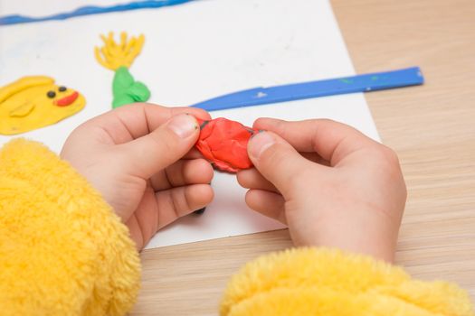 The child is holding a piece of red clay, close-up