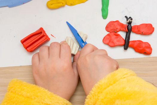 The child cuts off a piece of plasticine stack, close-up