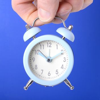 holding a small clock over a blue background