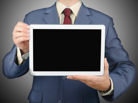 Businessman in suit holding up a tablet pc with blank screen for copy space