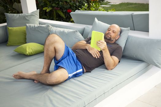 An image of a relaxing man reading on tablet pc