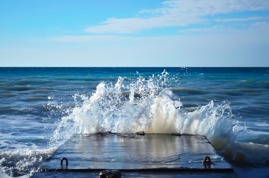 Powerful waves of the sea foam, breaking the concrete pier