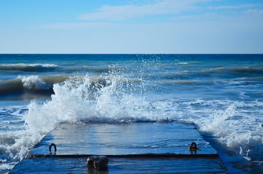 Powerful waves of the sea foam, breaking the concrete pier