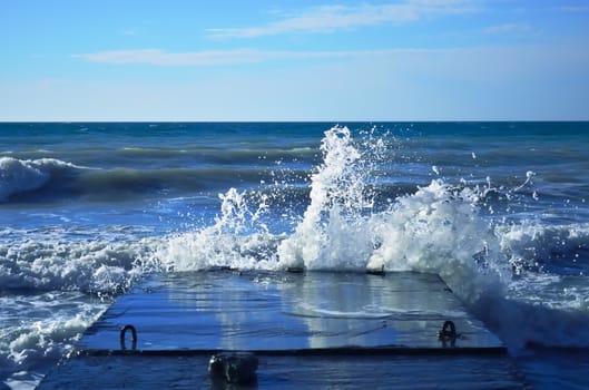 Powerful waves of the sea foam, breaking the concrete pier