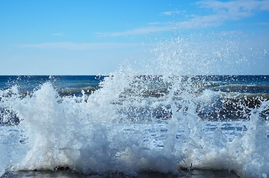 Powerful waves of the sea foaming, breaking against the rocky shore