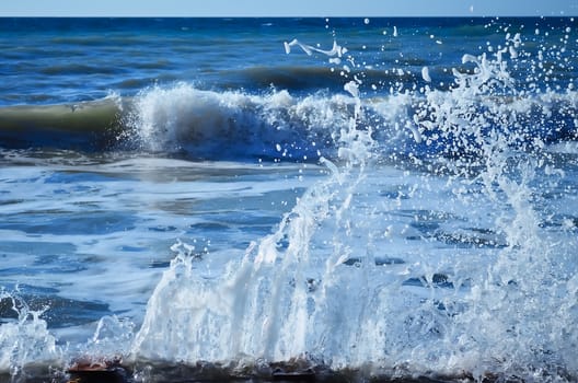 Powerful waves of the sea foaming, breaking against the rocky shore