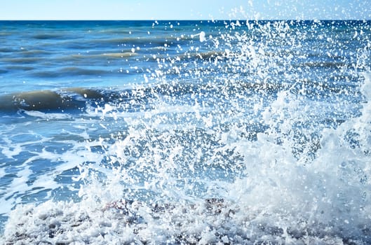 Powerful waves of the sea foaming, breaking against the rocky shore