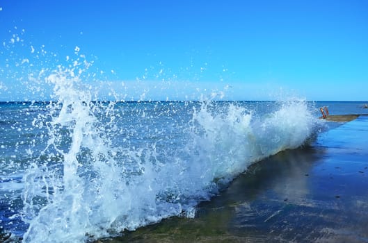 Powerful waves of the sea foam, breaking the concrete pier