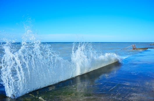 Powerful waves of the sea foam, breaking the concrete pier