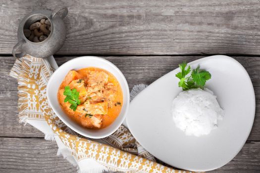 Chicken curry and rice served on a wooden surface