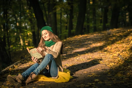 girl reading a book sitting on the track in a Park