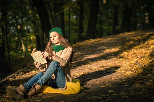 girl reading a book sitting on the track in a Park