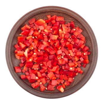 Sliced red pepper in a brown ceramic plate. Isolated on white background. Top view.