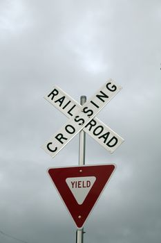 Close up of a railroad crossing and yield sign against a stormy sky