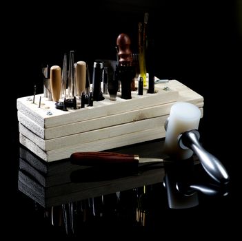 Arrangement of Various Tanneries Tools for Cutting and Piercing of Leather in Wooden Box with Reflection on Black Shiny background