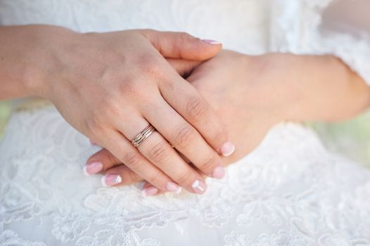 bride hand with a wedding ring on the background of dress.