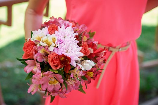 bridesmaid holding bridal bouquet on walk in summer park