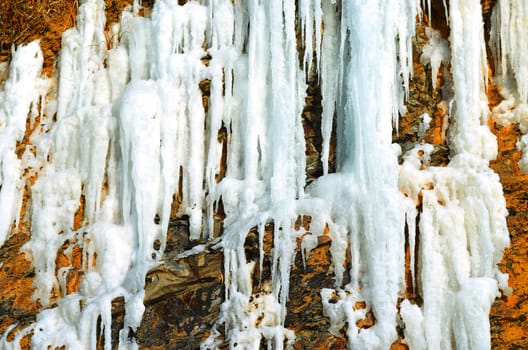Steep rock with a frozen waterfall near the sea